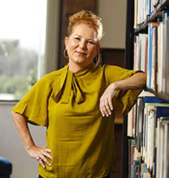 MCC Scholarship/Financial Aid recipient Paula Barlow leaning up against a bookshelf.